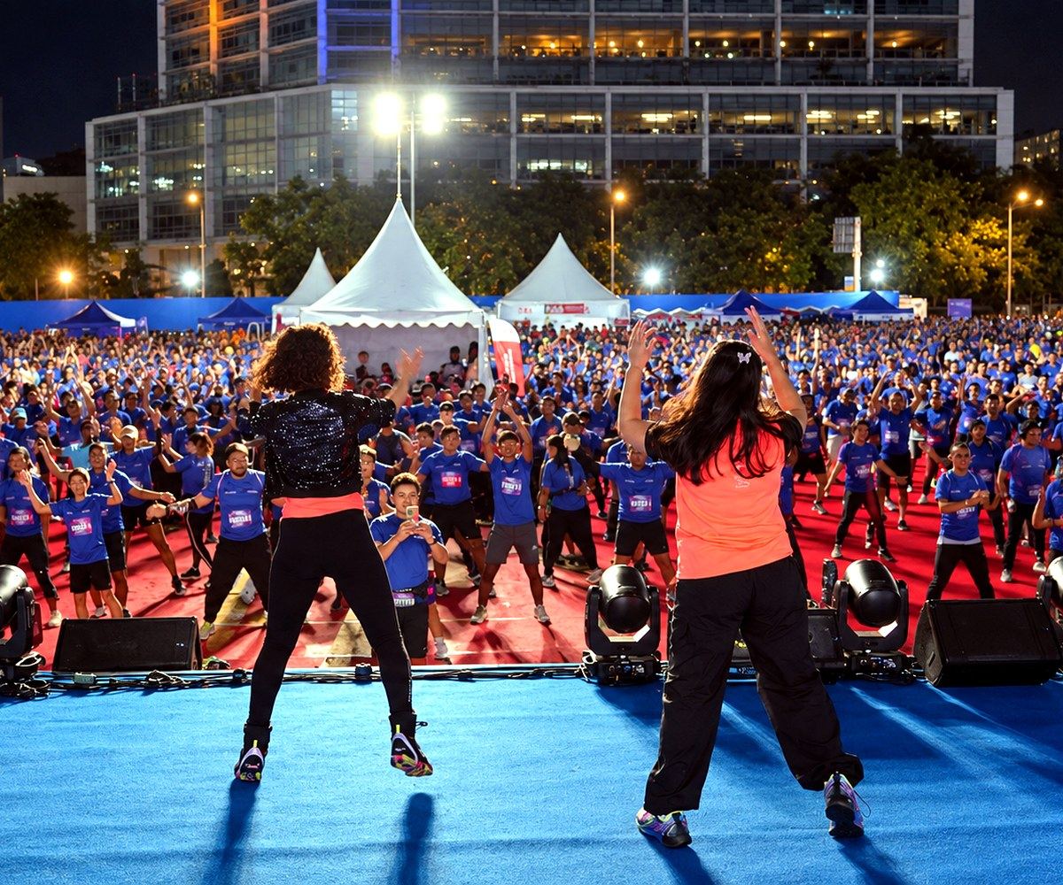 Thousands of runners warming up together under lights at a night race event managed by Abunduntia