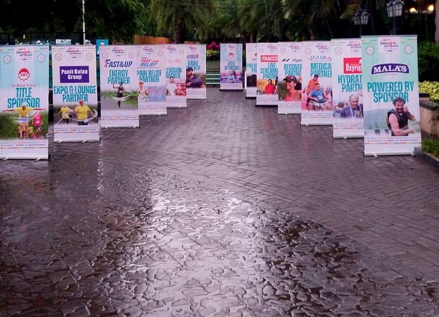 Row of sponsor banners along a tree-lined event venue walkway